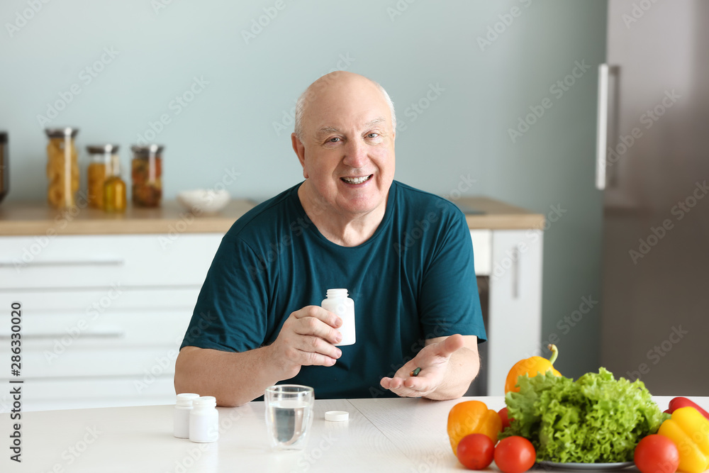 Elderly man taking medicine at home