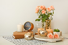 Beautiful Burning Candles With Rose Flowers, Books And Alarm Clock On Table