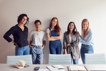 Portrait Of Young Female Business Team Standing By Table In Meeting Room In Modern Workspace