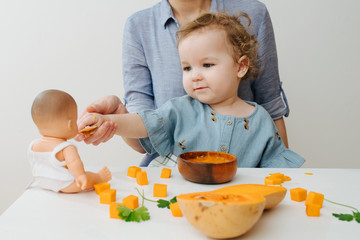 The girl feeding her doll pumpkin puree