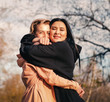 © olezzo - Multiethnic friendship and support concept, two young women a european and an asian sincerely hugging outdoor