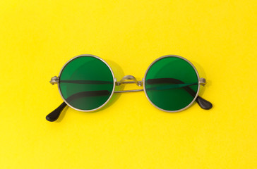 Vintage fashionable round green sunglasses on yellow background