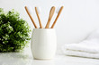 Four bamboo toothbrushes in a mug with a towel in the background