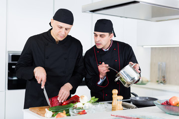 Wall Mural - Two male cooks are making salad on their work place in the kitchen