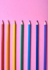 Color pencils on pink pastel background, close up. Set of colorful pencils, copy space. Crayons. Top view, flat lay. Back to school, college concept. Abstract background