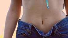 A Close Up View Of A Young Woman's Abdomen, Wearing Blue Jeans With An Open Top Button