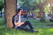 © PAVEL GERASIMENKO - A young guy with purple hair sits in a park and uses the phone