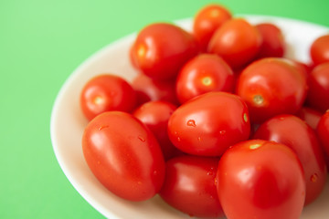 red tomatoes in white plate on green background