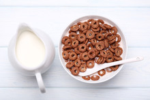 Chocolate Corn Flakes In Bowl With Milk And Spoon On Wooden Table
