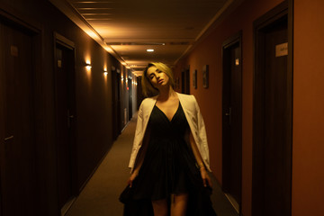 Luxury girl in black dress at night in the hotel corridor.