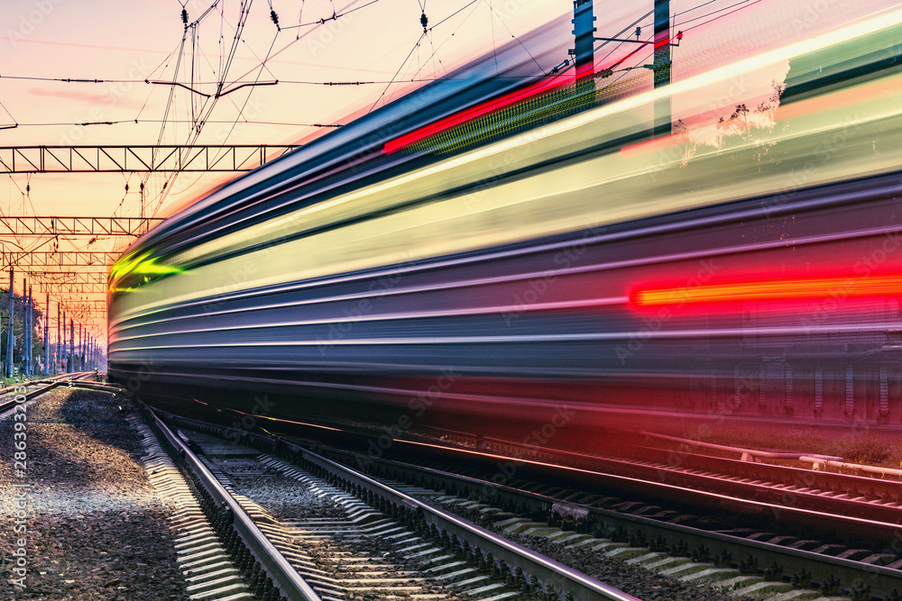 Passenger train moves fast at sunset time. - obrazy, fototapety, plakaty 