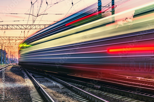 Fotografía Passenger train moves fast at sunset time.