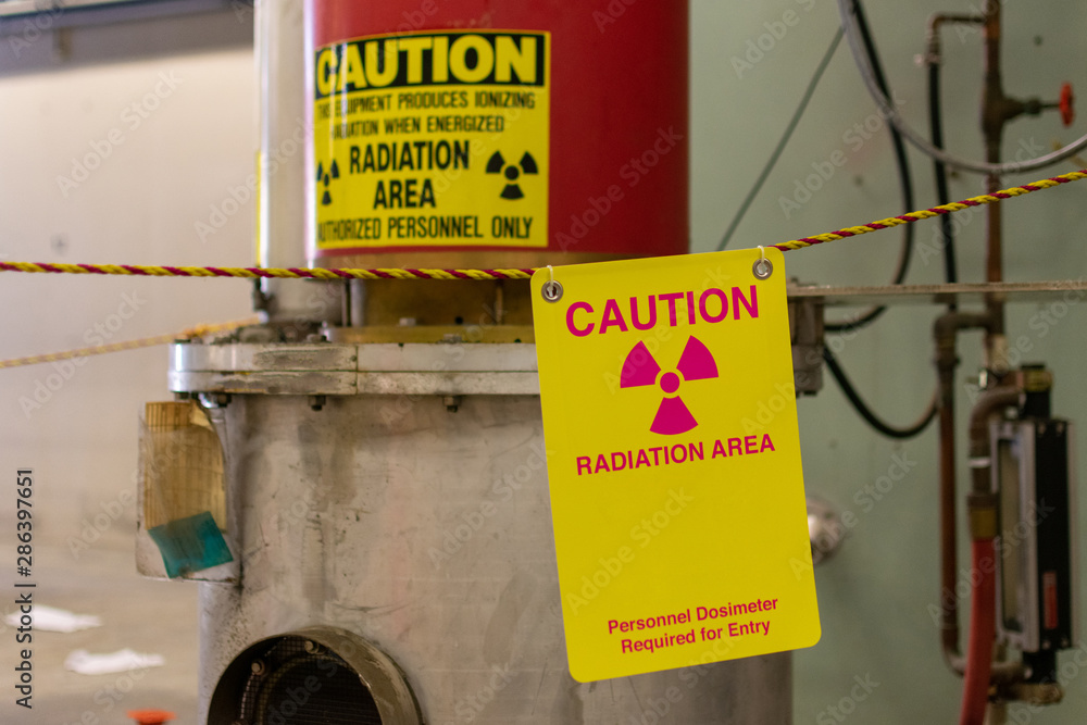 Ionizing radiation hazard symbol, caution radiation area and personnel dosimeter required text on yellow warning sign displayed on the equipment that produces ionizing radiation  - obrazy, fototapety, plakaty 