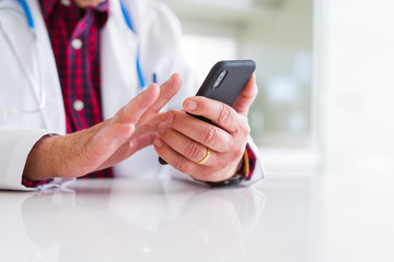 Wall Mural - Close up of doctor man hands using smartphone and wearing stethoscope