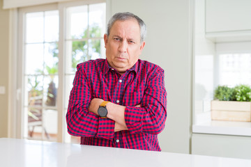 Wall Mural - Handsome senior man at home skeptic and nervous, disapproving expression on face with crossed arms. Negative person.