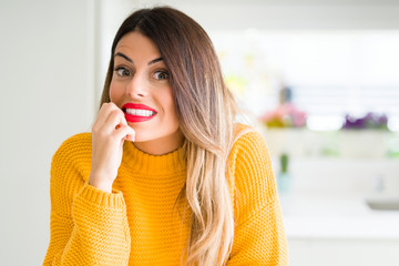 Canvas Print - Young beautiful woman wearing winter sweater at home looking stressed and nervous with hands on mouth biting nails. Anxiety problem.