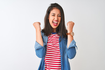 Young chinese woman wearing striped t-shirt and denim shirt over isolated white background celebrating surprised and amazed for success with arms raised and eyes closed. Winner concept.