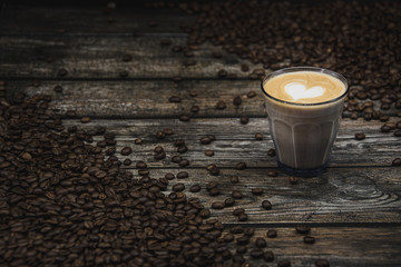 glass of coffee latte with beans on brown wooden background 