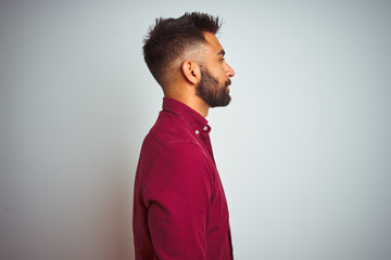 Wall Mural - Young indian man wearing red elegant shirt standing over isolated grey background looking to side, relax profile pose with natural face and confident smile.