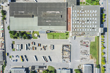 Aerial Top View Of Modern Industrial Building And Warehouse With Parked Trucks And Cars. Drone Photo