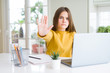 © Krakenimages.com - Beautiful young girl studying for school using computer laptop with open hand doing stop sign with serious and confident expression, defense gesture