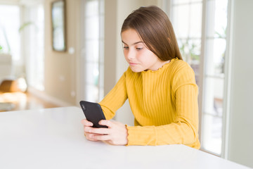 Beautiful young girl kid sending a message using smartphone with a confident expression on smart face thinking serious