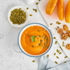 Wall Mural - Creamy pumpkin soup with seeds, top view light white background