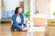 © Krakenimages.com - Young plus size woman sitting on the floor around cardboard boxes moving to a new home looking away to side with smile on face, natural expression. Laughing confident.