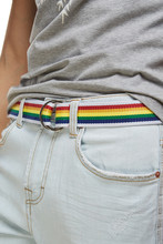 Cropped Close-up Shot Of A Man Dressed In A Gray Graphic Tee And Light Blue Jeans With A Belt. The Textile Belt With Multicoloured Stripes Is Made Of Textured Fabric And Equipped 