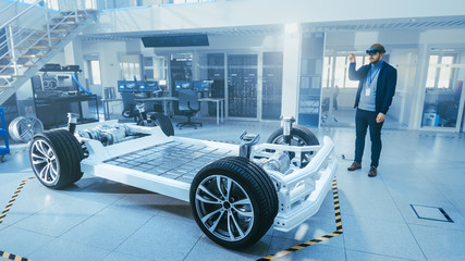Leinwandbilder - Automotive Engineer Working on Electric Car Chassis Platform, Using Augmented Reality Headset. In Innovation Laboratory Facility Concept Vehicle Frame Includes Wheels, Suspension, Engine and Battery.