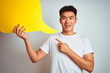 © Krakenimages.com - Asian chinese man holding speech bubble standing over isolated white background very happy pointing with hand and finger