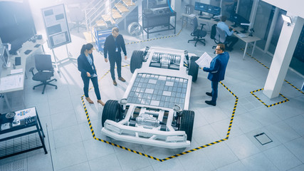 Wall Mural - Team of Automobile Design Engineers in Automotive Innovation Facility. They are Working on Electric Car Platform Chassis Prototype that Includes Wheels, Suspension, Hybrid Engine and Battery.