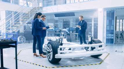 Poster - Automotive Design Engineers Looking at Technical Drawings of a Electric Car Chassis Prototype. In Innovation Laboratory Facility Concept Vehicle Frame Includes Wheels, Suspension, Engine and Battery.