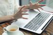 © Dana Keli - laptop on the table. female tense hands with outstretched fingers above the computer. white cup of tea next to a laptop. Stress, irritation.