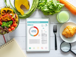 Wall Mural - Calories counting , diet , food control and weight loss concept. tablet with Calorie counter application on screen at dining table with salad, fruit juice, bread and vegetable