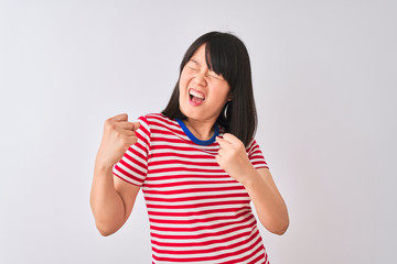 Wall Mural - Young beautiful chinese woman wearing red striped t-shirt over isolated white background very happy and excited doing winner gesture with arms raised, smiling and screaming for success. 