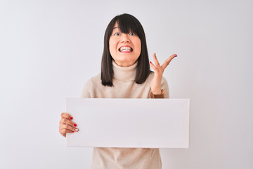 Wall Mural - Young beautiful Chinese woman holding banner standing over isolated white background very happy and excited, winner expression celebrating victory screaming with big smile and raised hands