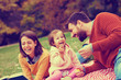 © Cherries - Happy little girl on picnic with her parents blowing dandelions