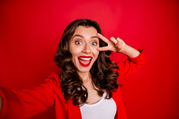 Sticker - Close up photo of excited stylish girl making v-signs taking selfie screaming isolated over red background