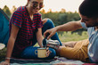 © cherryandbees - happy young couple drinking coffee, camping together by the river