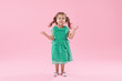 © oes - Funny little kid, toddler girl in fashionable green dress isolated on pink background