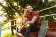 © Drobot Dean - Attractive cheerful young man sitting at the skate park ramp