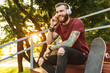 © Drobot Dean - Attractive cheerful young man sitting at the skate park ramp