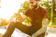 © Drobot Dean - Attractive cheerful young man sitting at the skate park ramp