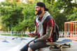 © Drobot Dean - Attractive cheerful young man sitting at the skate park ramp