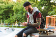 © Drobot Dean - Attractive cheerful young man sitting at the skate park ramp