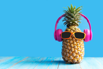 Summer in the party.  Hipster Pineapple Fashion in sunglass and music bright beautiful color in holiday, Creative art fruit for tropical style on the beach vibes, blue background.  Fashion Summer 