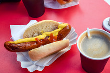 Fried Sausage In A Bun With Mustard And Ketchup With Coffee In A Cafe