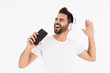 © Drobot Dean - Image of unshaven smiling man singing while listening music on cellphone and headphones