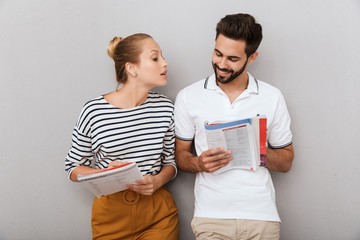 Poster - Loving couple friends man and woman indoors isolated over grey background holding copybooks studying.